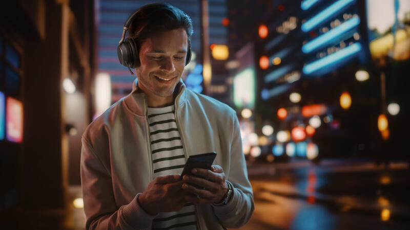 Image of user pairing Yealink BH76 Plus Teams headset with smartphone in a fast-paced city environment.