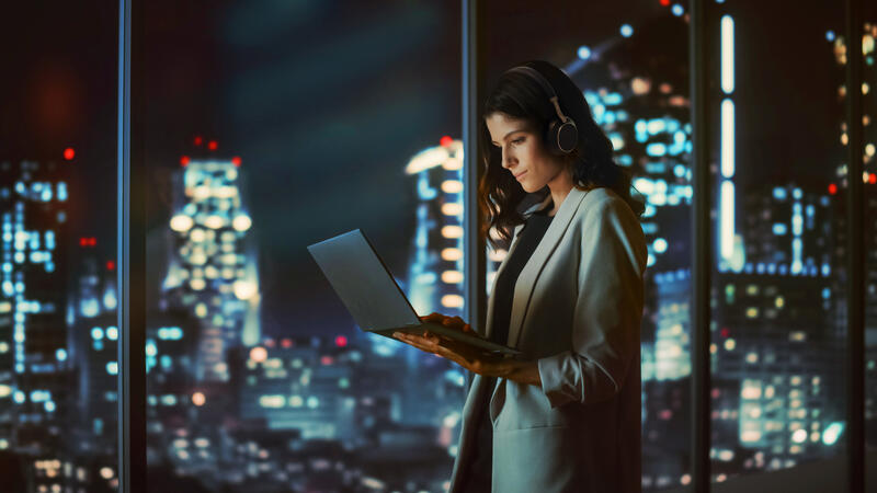 Image of user pairing Yealink BH76 Plus Teams headset with laptop in a modern office environment.